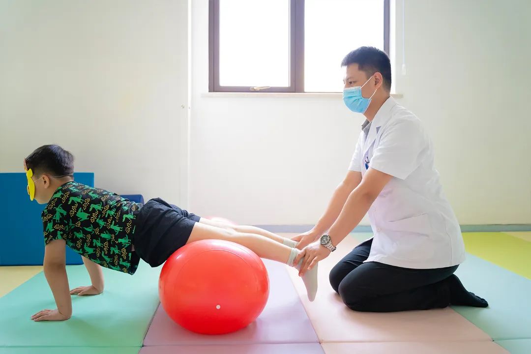 患儿坐在巴氏球上,治疗者双手固定患儿髋部,前后左右四个方向晃动球